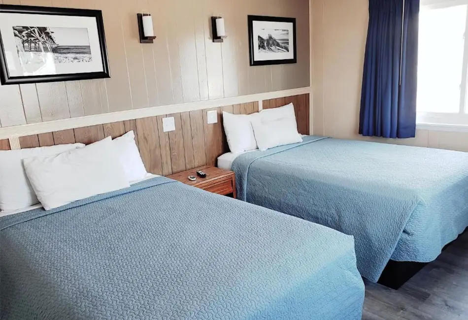 Two beds beside a window in a Colonial Inn room with a pullout sofa