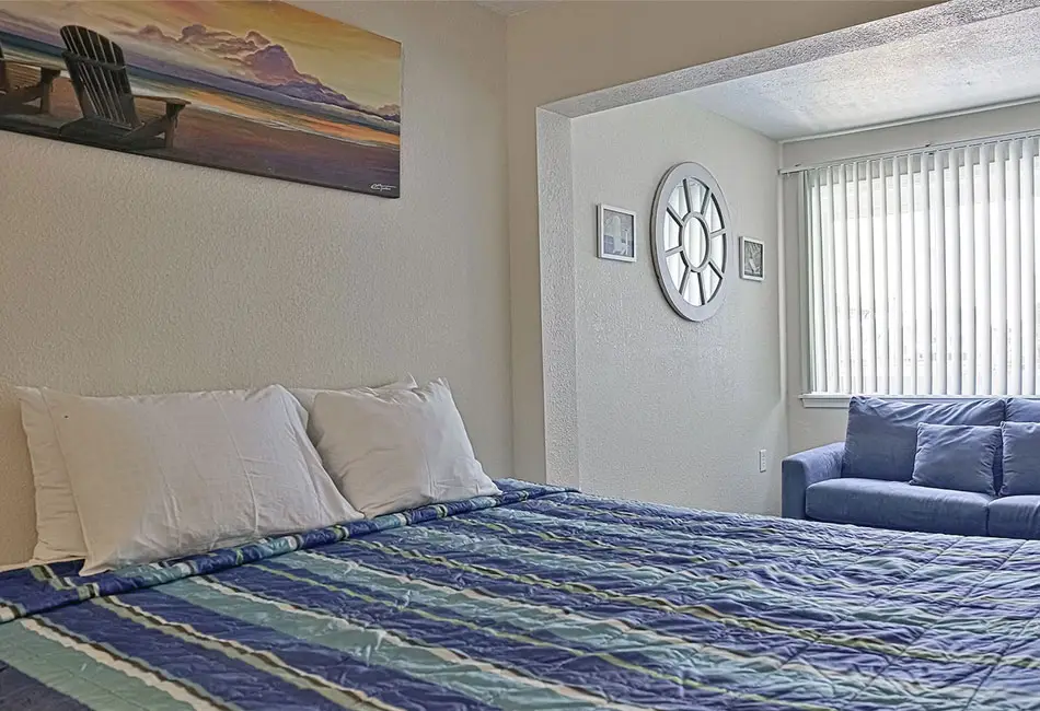 Bed and blue sofa in a two-king kitchen unit at Colonial Inn