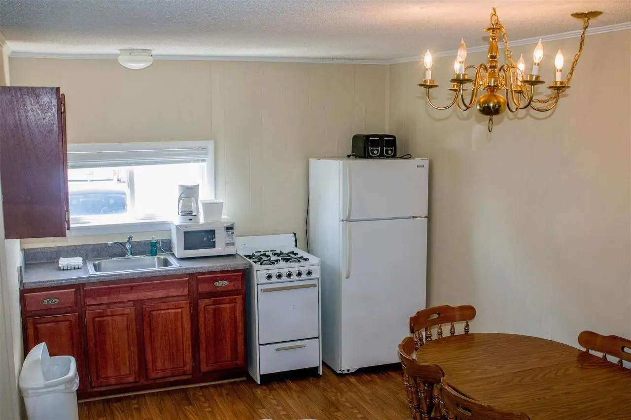 A full apartment kitchen with a cooker, fridge and microwave, and a round dining table under a chandelier