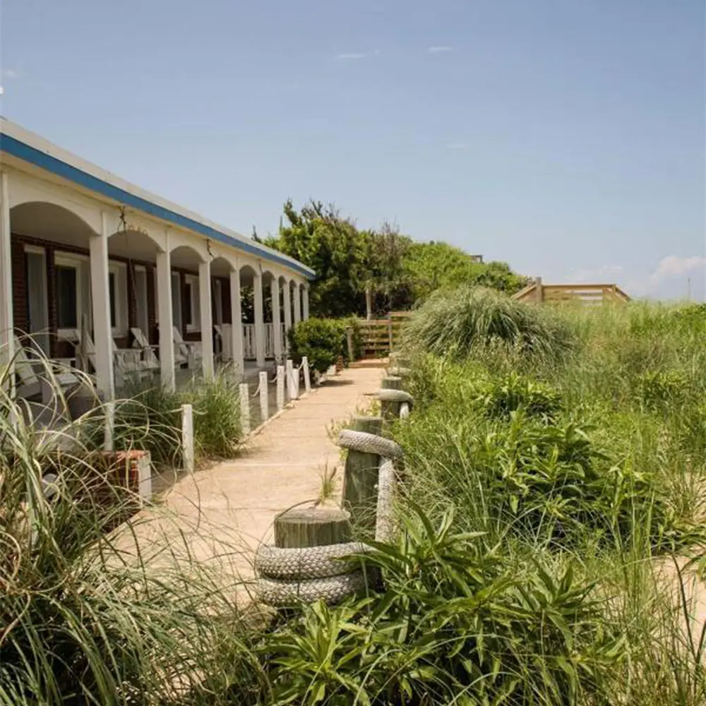 The motel\u2019s long white colonnade running beside the dune, with sea oats growing up against it