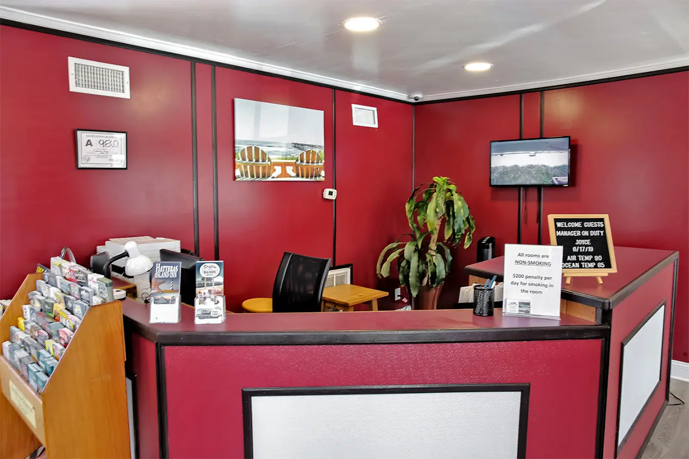 The Colonial Inn’s front desk, with its deep red wall, a leaflet rack and a welcome sign