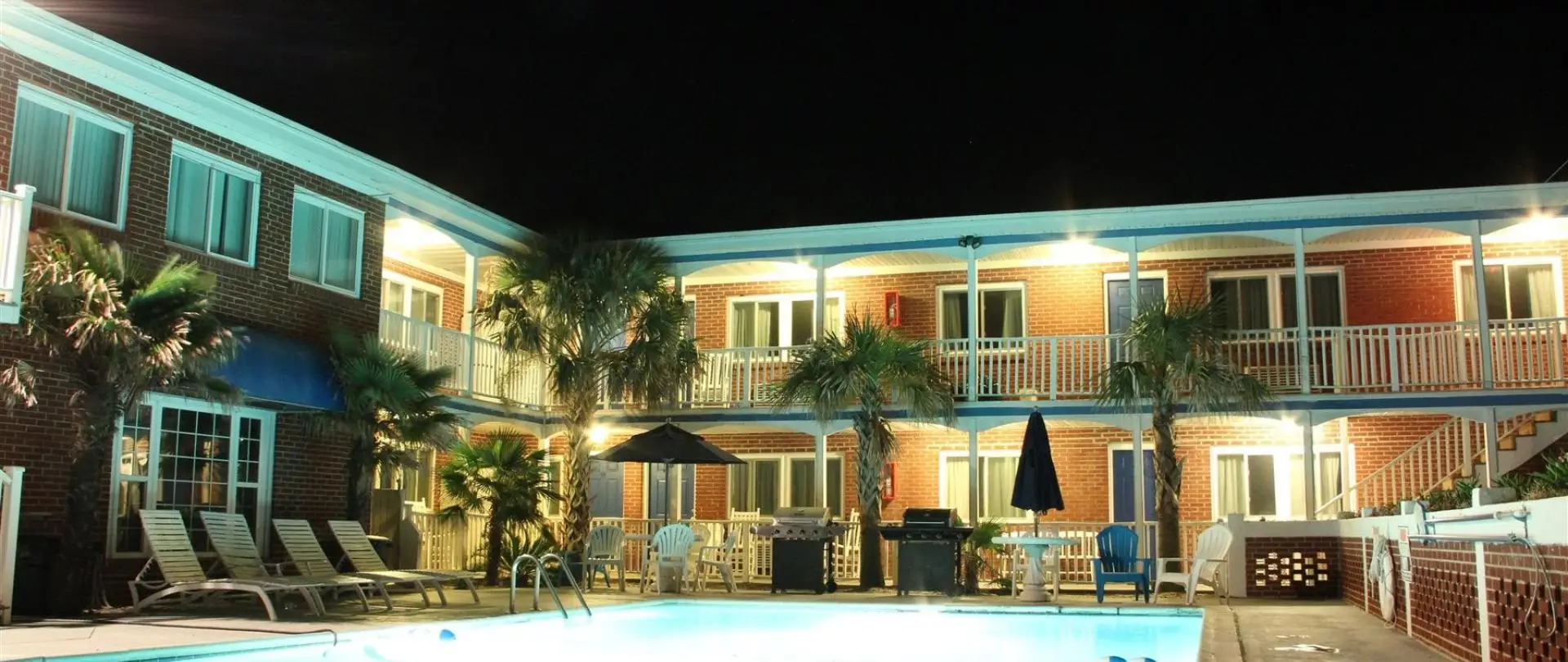 The motel lit up at night, with the pool in the foreground
