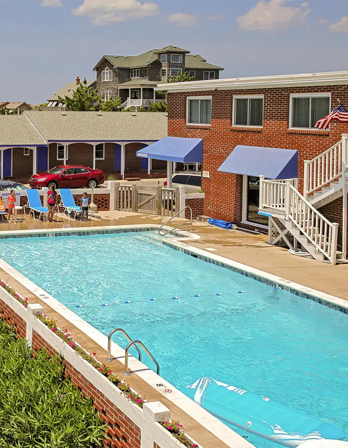 The outdoor pool and the motel behind it, seen across the dune grass