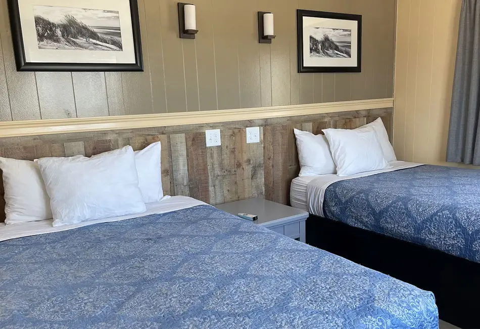 Two double beds with blue covers in a Colonial Inn guest room