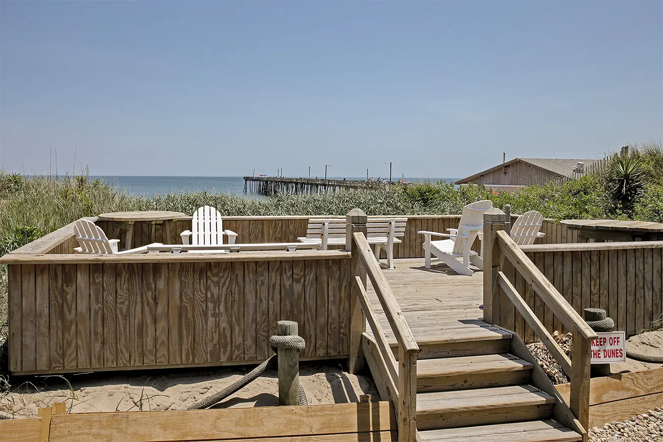 Adirondack chairs on the wooden sun deck over the dune, looking out to the ocean and the pier