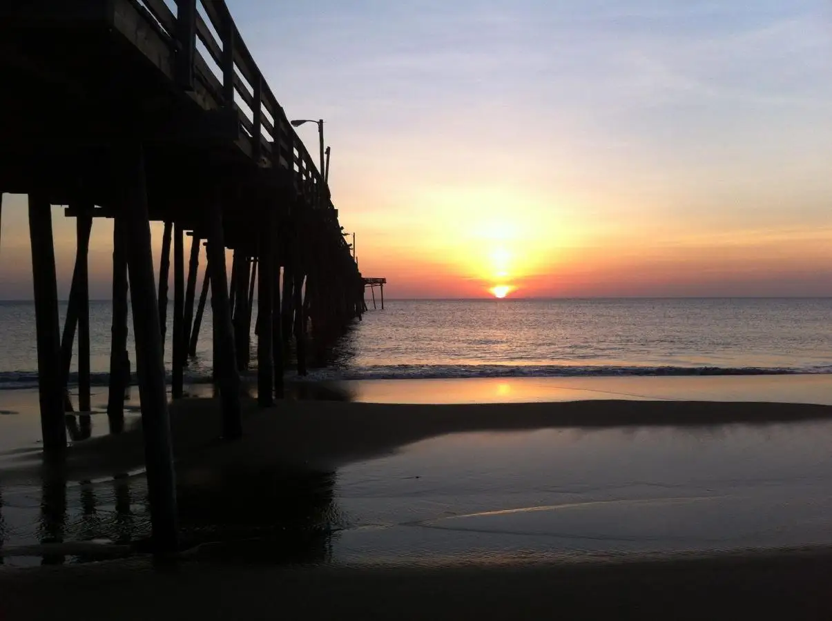 The sun rising over the ocean beneath the fishing pier